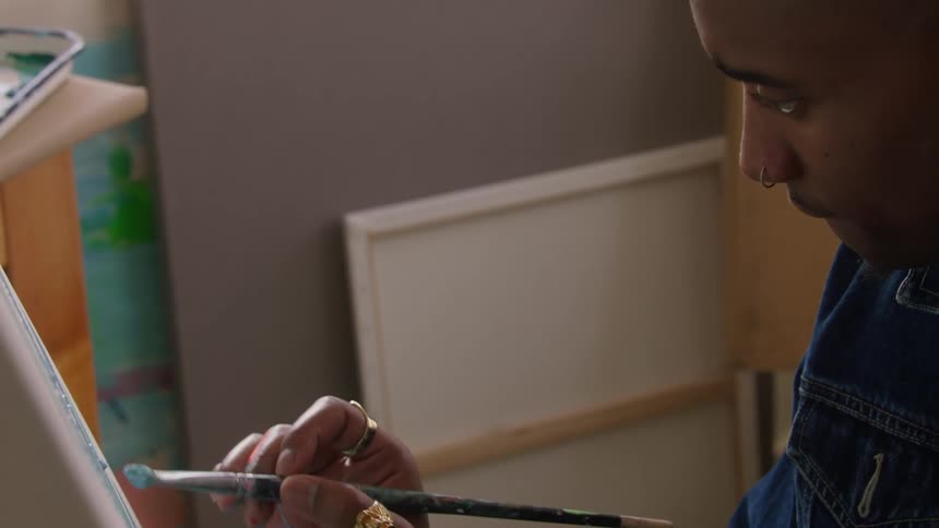 Man paints canvas with brush in art studio