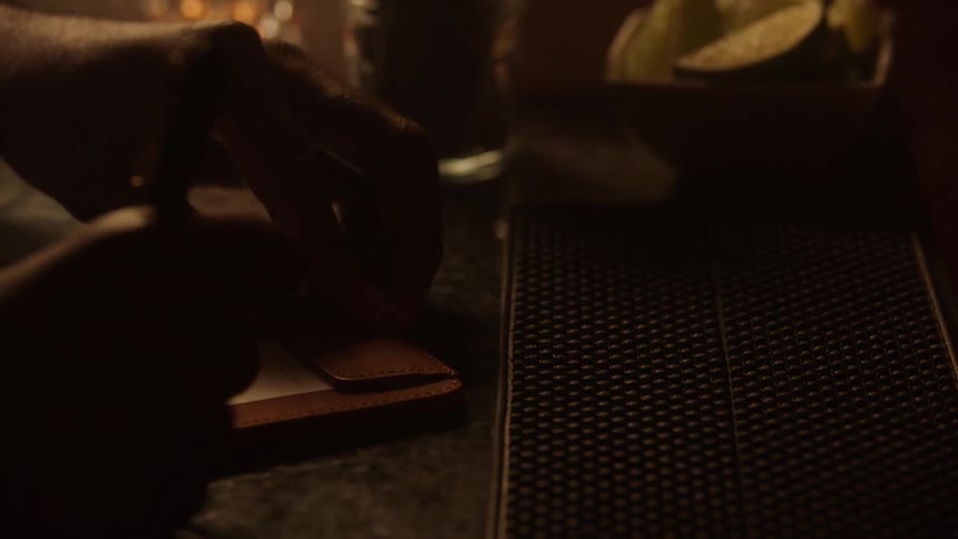 Man signs his bar tab and the bartender takes it off the counter