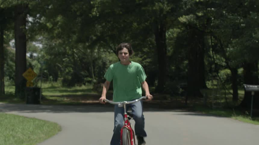A boy is riding his bicycle down the street