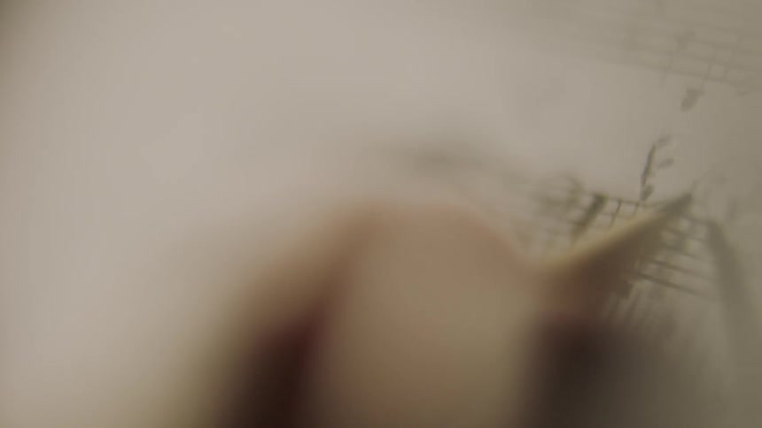 A man is using a pencil to change sheet music
