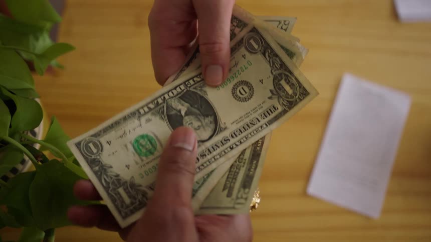 One person hands money to another person across a counter