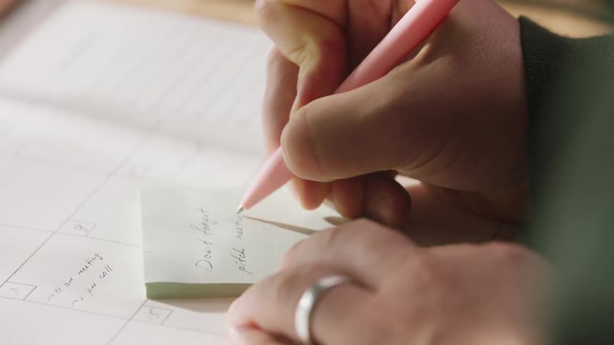 A person writing notes on a sticky note in an office