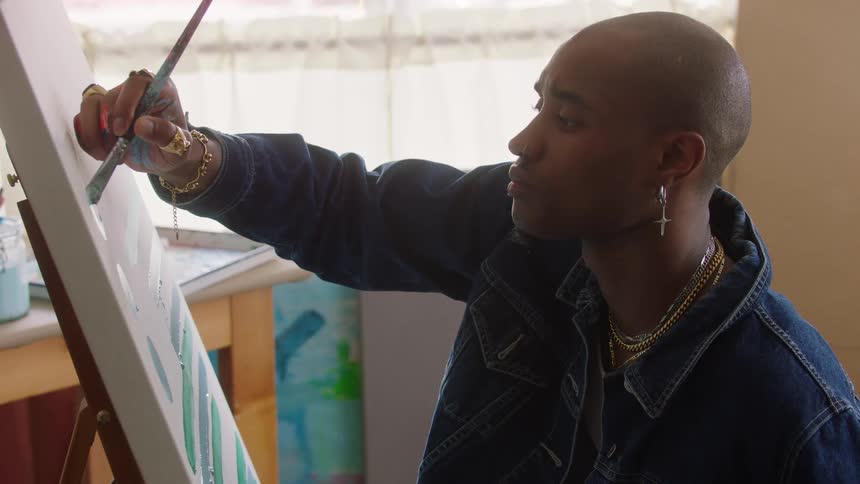 Artist paints on a canvas set on an easel under natural light