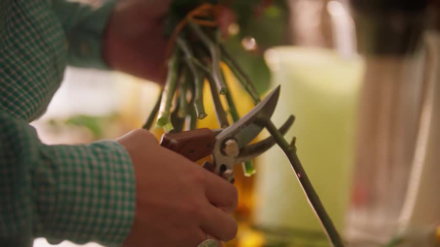 Florist clipping the stems on a bouquet of flowers and handing them to a customer