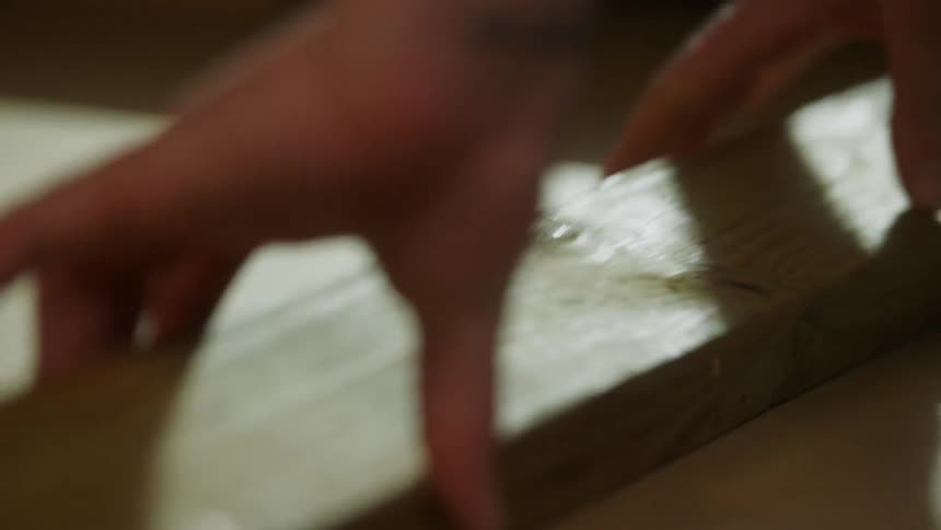 Hand slides over a piece of wood in preparation for manual work