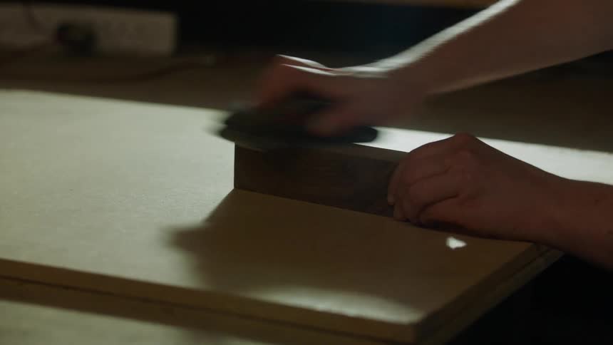 A persons hand holding a brush to clean the surface of a rectangular stone