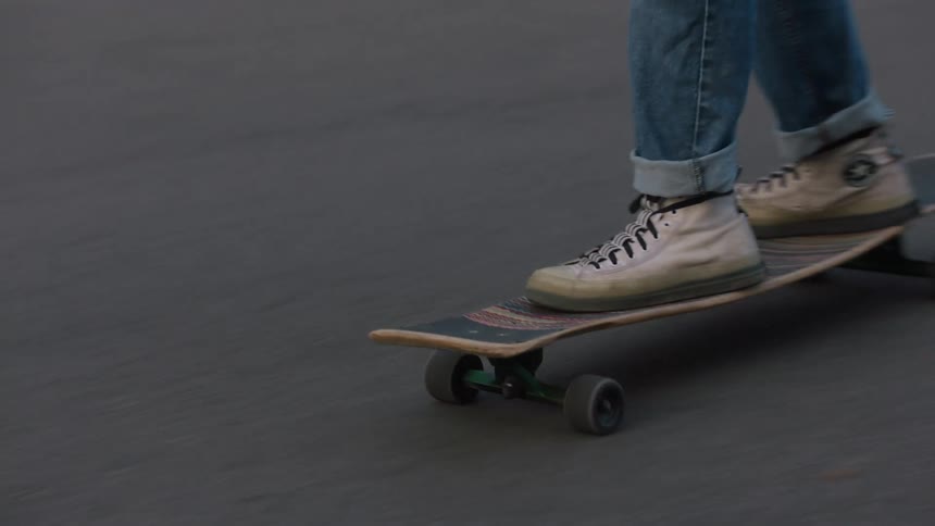 The person rides their skateboard on the road