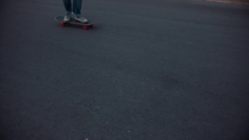 Person balances on a moving skateboard over the asphalt