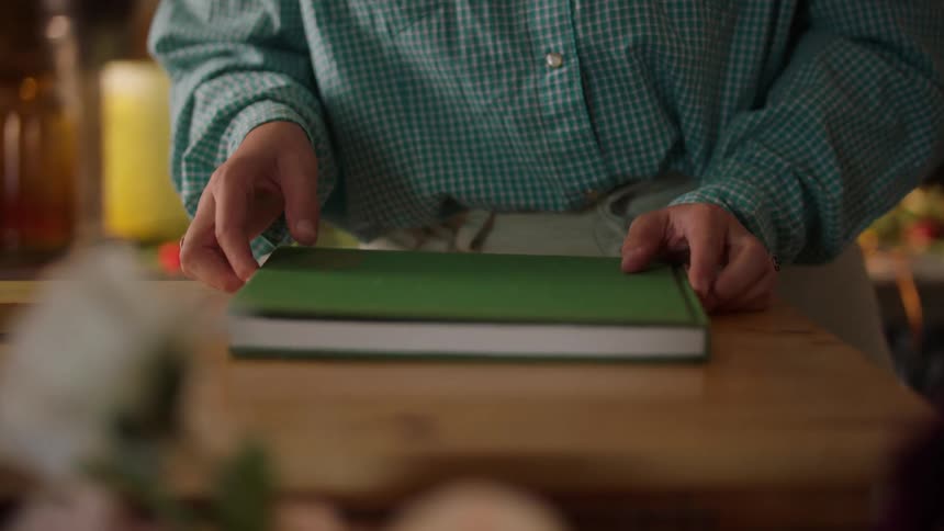 Person flips through a book on the table in a cozy setting