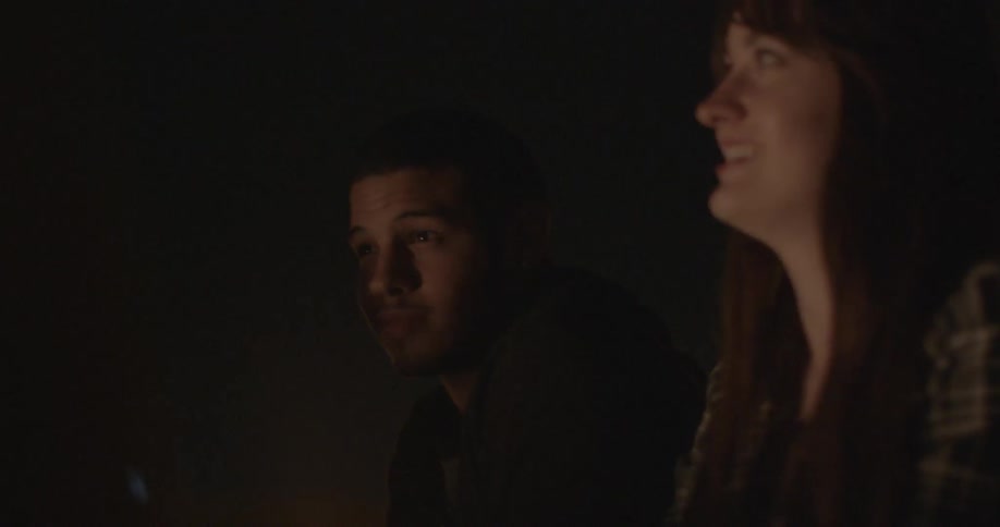 Man and woman sit outside in the dark