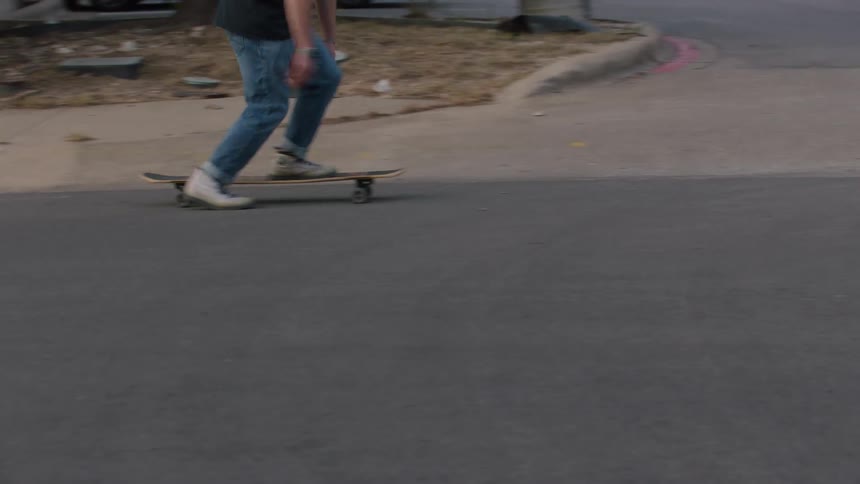 Teenage boy riding a skateboard on a neighborhood street