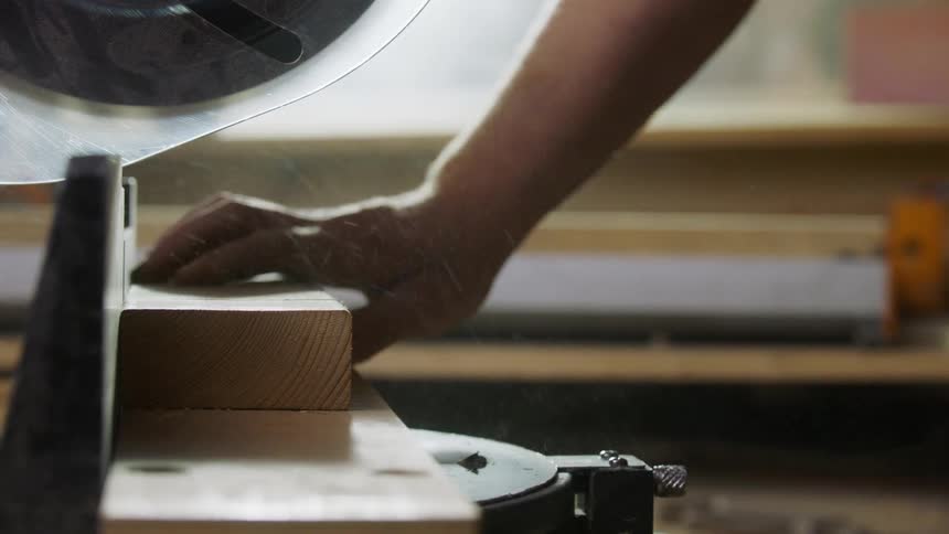 A person cutting wood with a chop saw