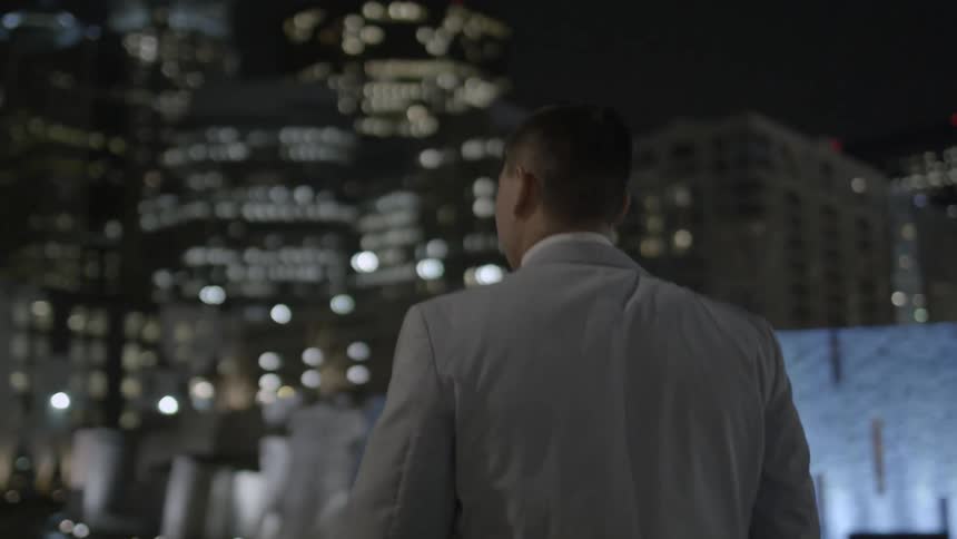 Man looks out at skyscrapers at night