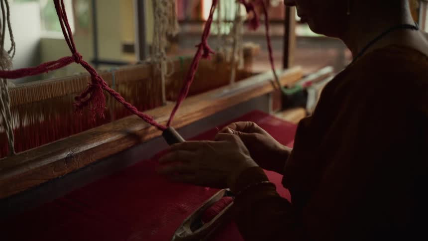 A person working on sewing in a loom