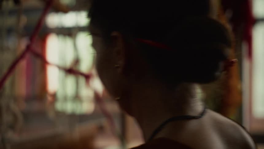 Focused woman working with red threads in a naturally lit craft setting
