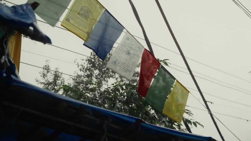 A building with flags tied across its roof stands beneath utility wires stretching overhead at midday
