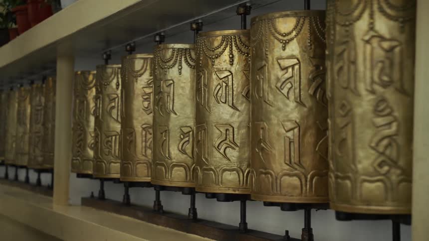 Tibetan prayer wheels with embossed inscriptions aligned on horizontal axis