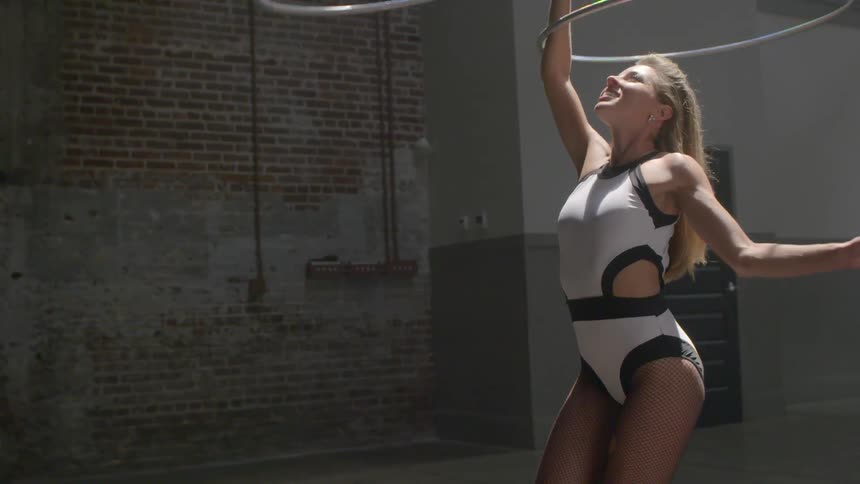 A woman hula hoops on her arm then dances a little