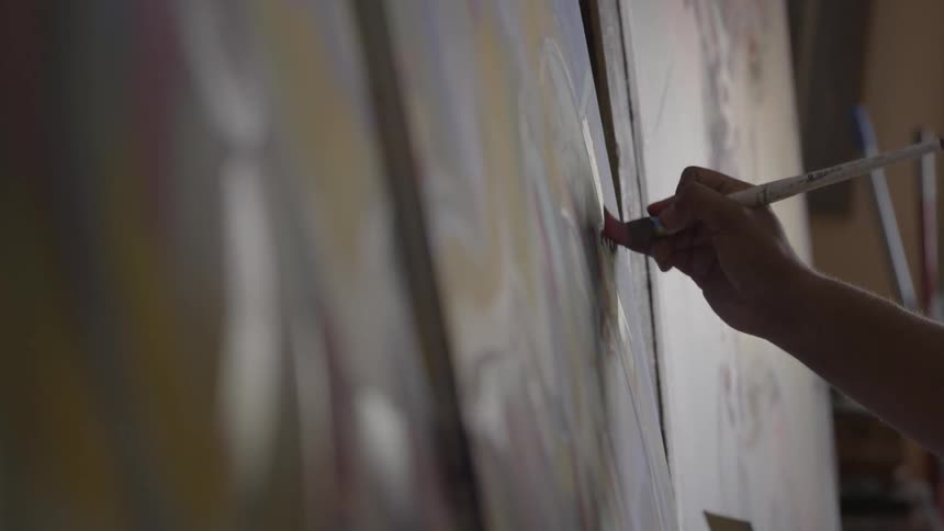 An artist paints on a canvas