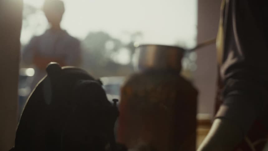 Person pouring liquid with a ladle in a sunlit setting