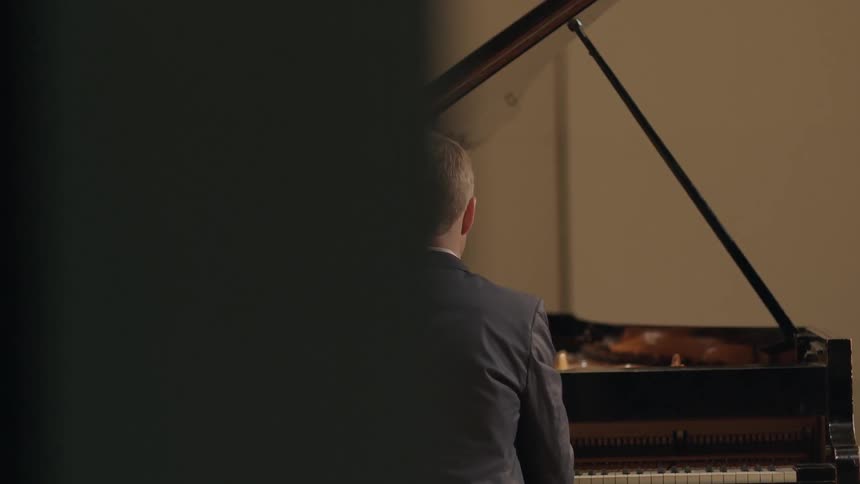 Man is sitting at and playing a piano