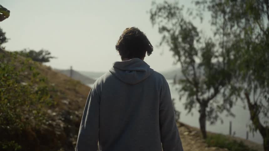 Man walks on a trail near the water on an autumn day