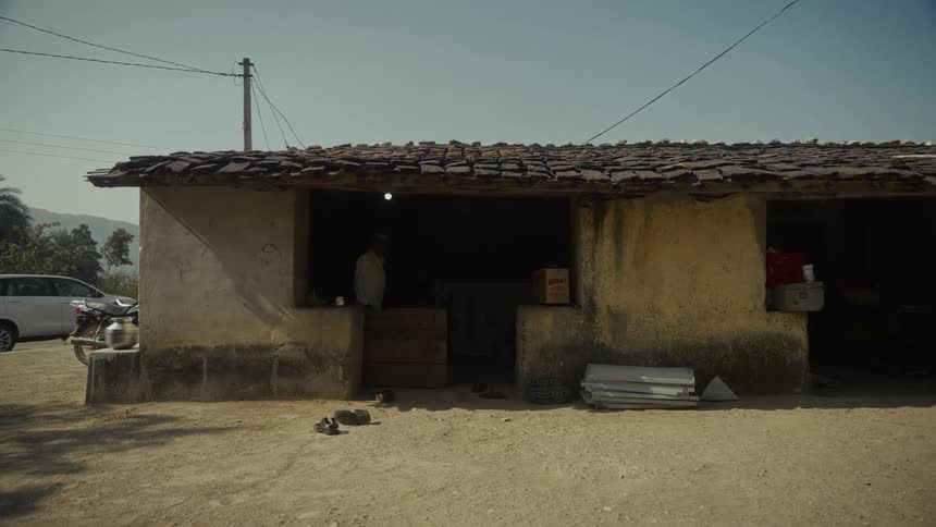 Rustic singlestory building with tiled roof and scattered items in front in rural area