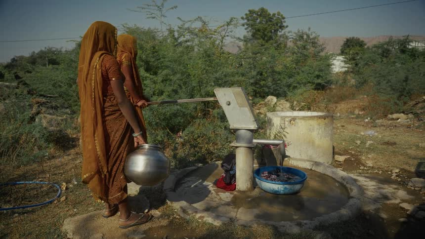 Two women pumping water outdoors