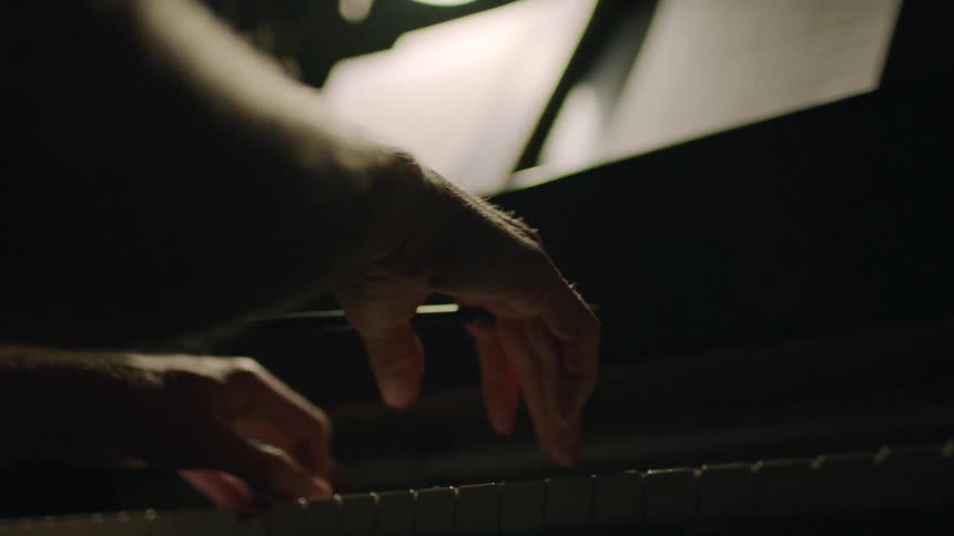 A person is playing a piano in the dark