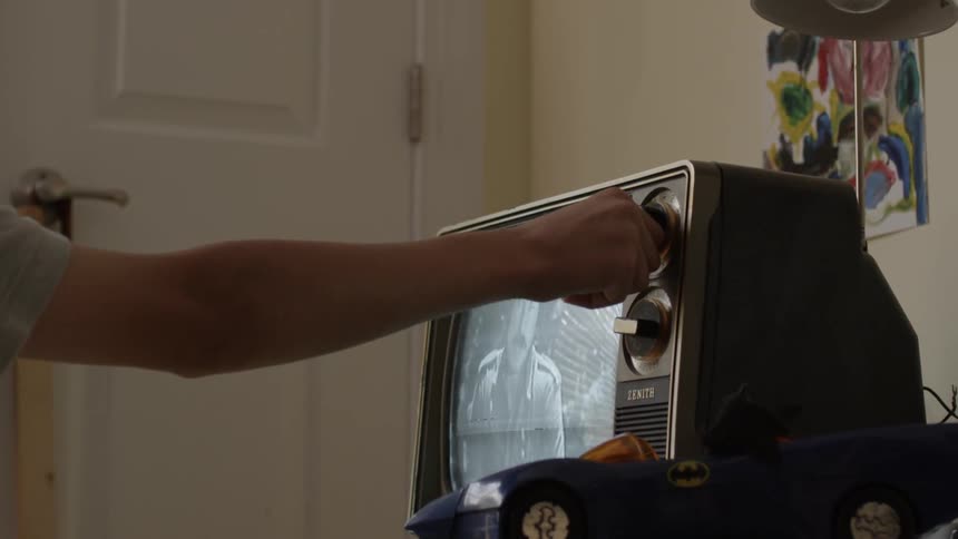 Person tuning an old black and white television