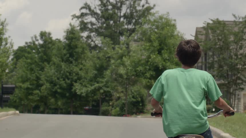 A boy rides a bike up a hill in a neighborhood