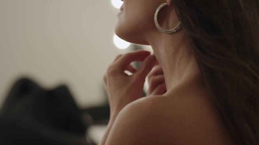 A woman is putting on earrings