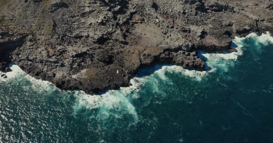 Rocky coast with waves crashing on dark stones under cloudy sky