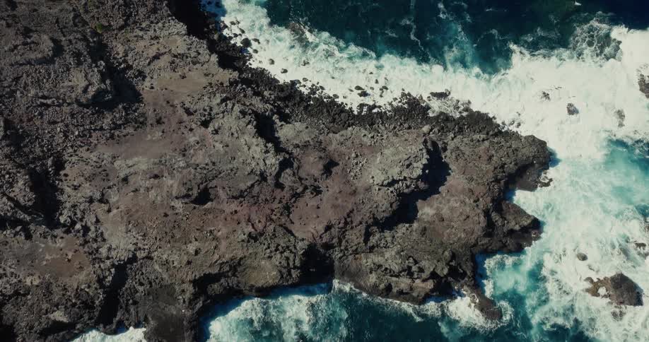 Rocky coast with crashing waves and water in shades of blue and turquoise