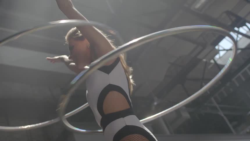 A woman twirls two hula hoops at once