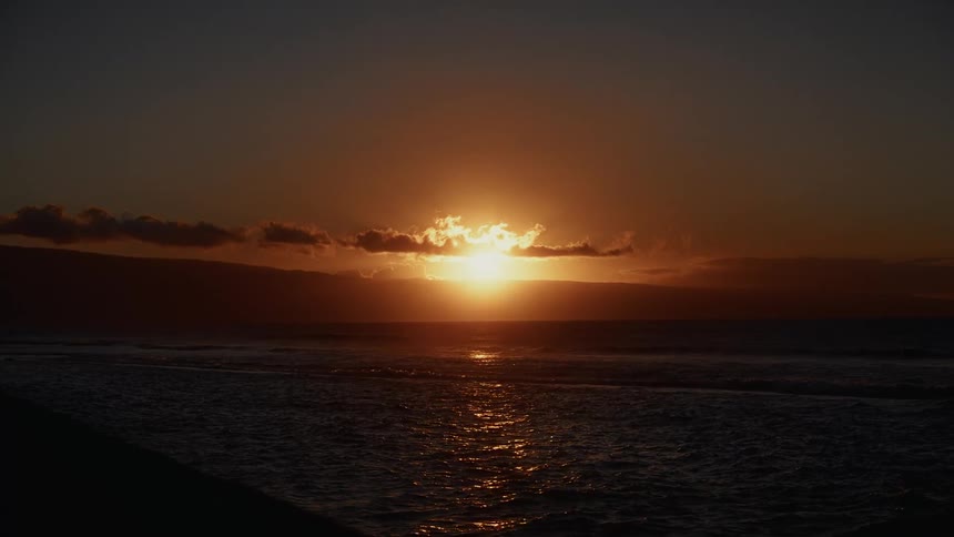 Sunset over the ocean with partially obscured sun and golden reflections on the waves