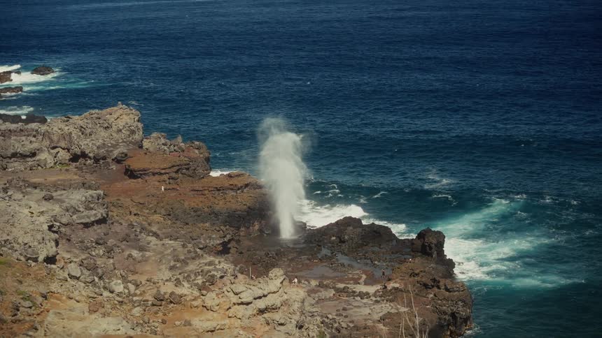 Blowhole jetting water on a cliff next to the ocean outdoors during day time