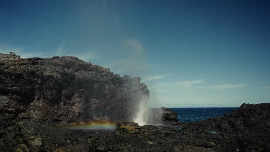 A wave splashing on the rocky shoreline at the beach