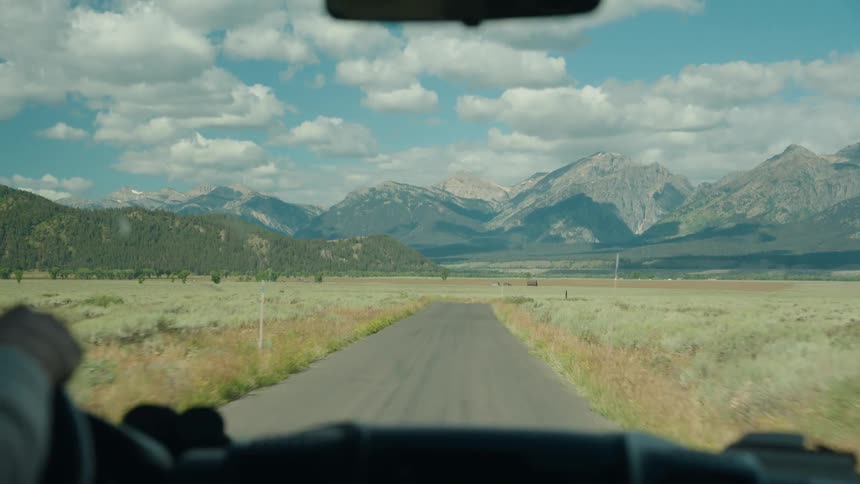 The vehicle is traveling on the dirt road towards the mountains