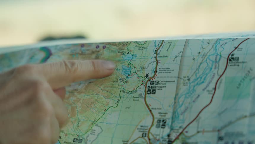A persons finger pointing to a paper map with various lines and drawings