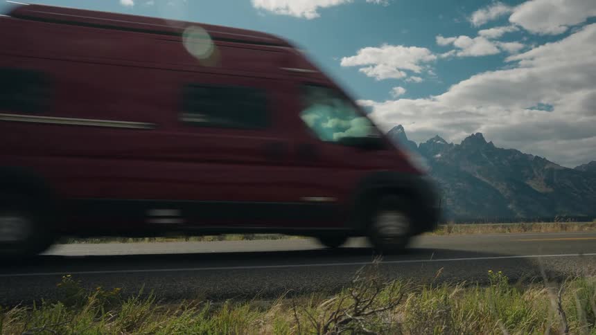 Van travels on a rural highway with mountains in the distance