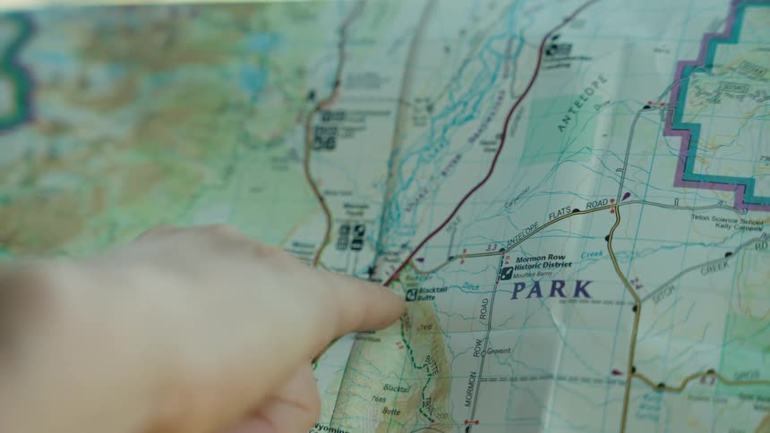 A finger points to a specific location on a detailed paper map