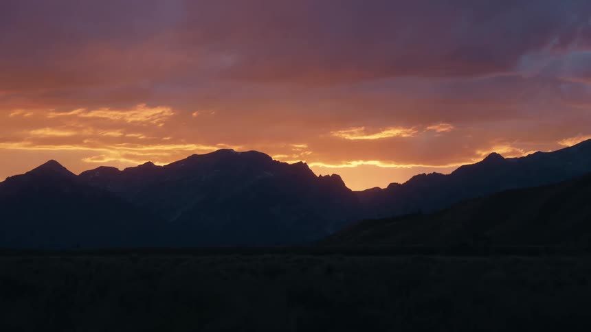 Mountain landscape at sunset with vibrant sky in shades of orange yellow and purple