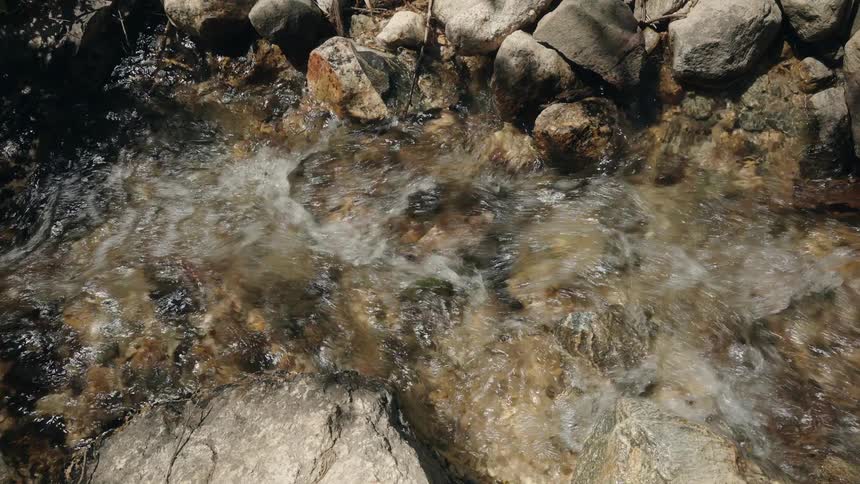 Water stream flows over rocks in a shallow bed