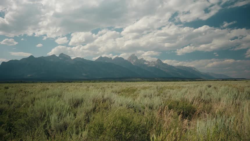 Natural landscape with a plain field in the foreground and a mountain range on the background outdoors during day time