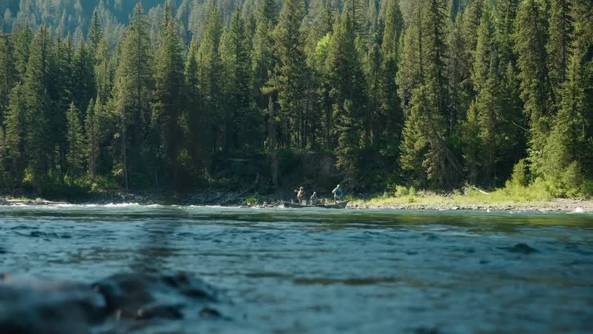 Fishermen in a small boat on a river off the forested coast