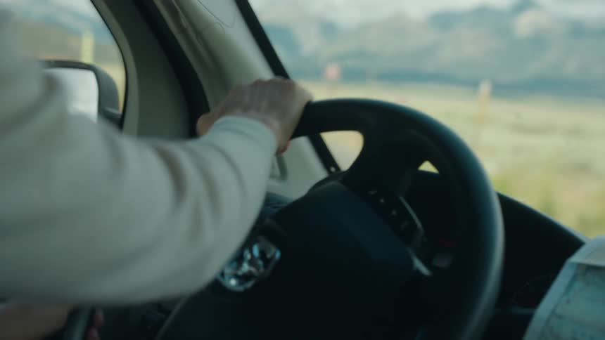 The man turns the steering wheel on the small road