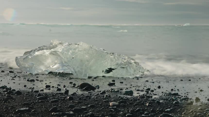 Time lapse of ocean water washing ashore around a piece of sea ice