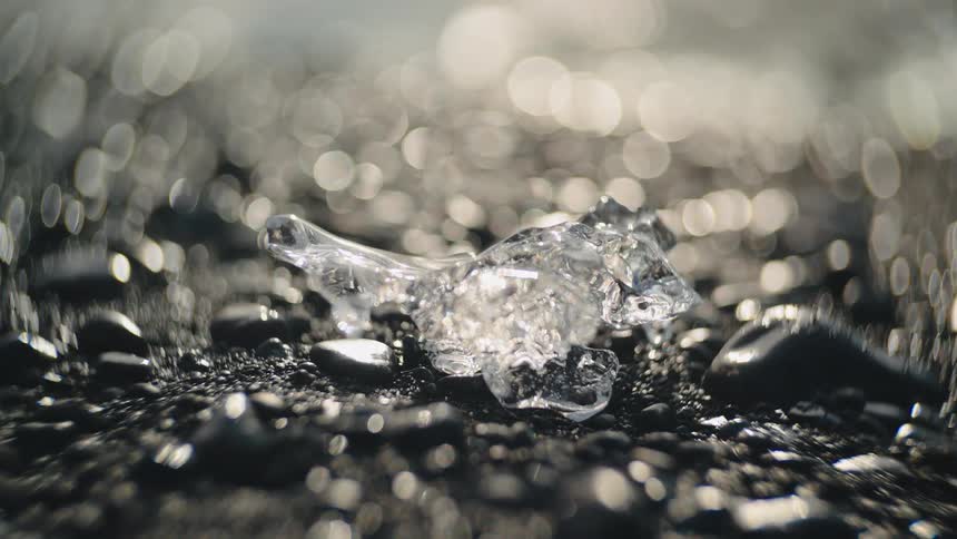A chunk of ice sitting on a rocky floor outdoor