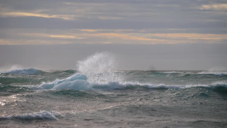 Sea waves breaking over an iceberg on the ocean outdoors during day time